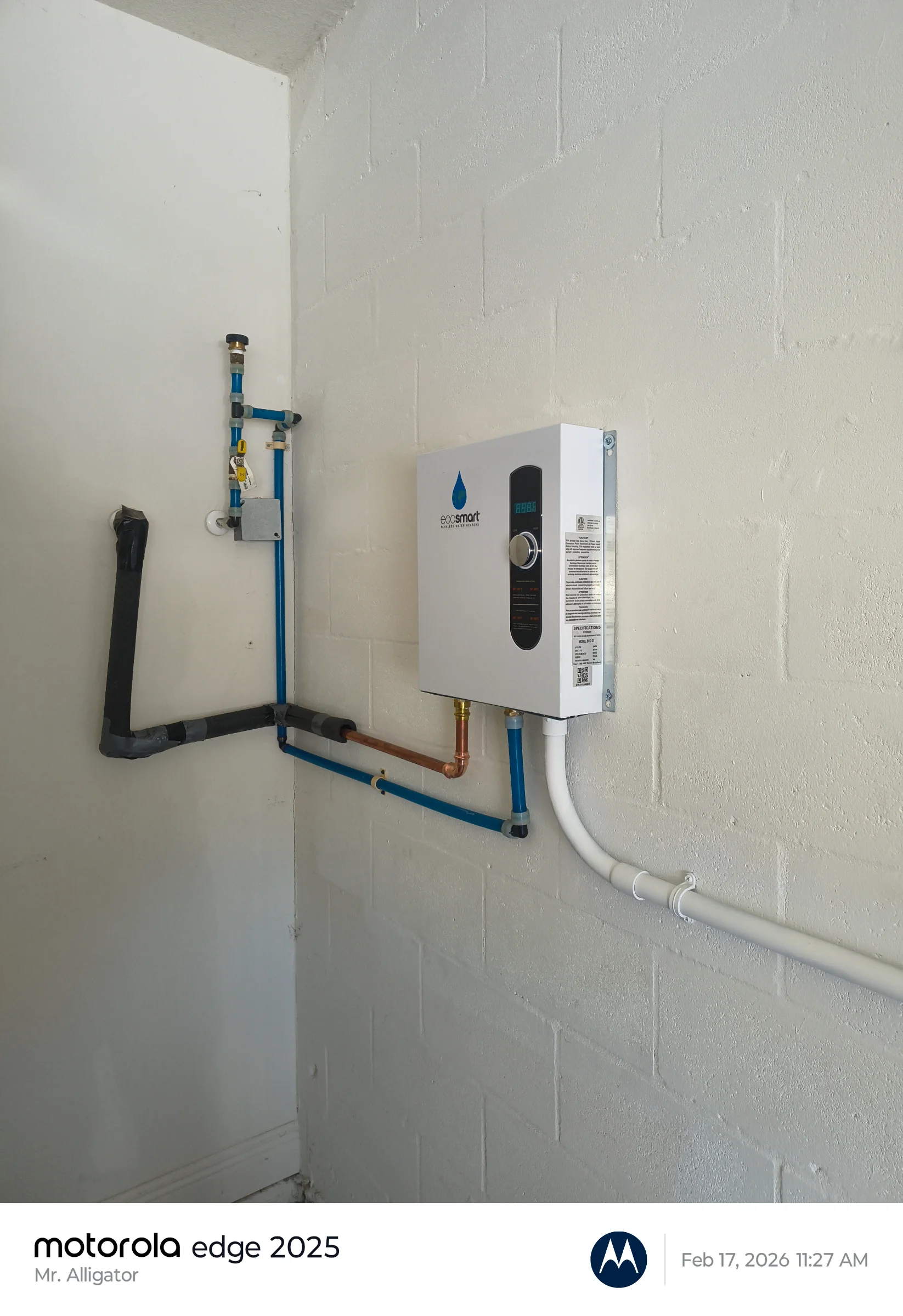 Newly installed wall-mounted EcoSmart tankless electric water heater with clean PEX plumbing and electrical conduit integration.